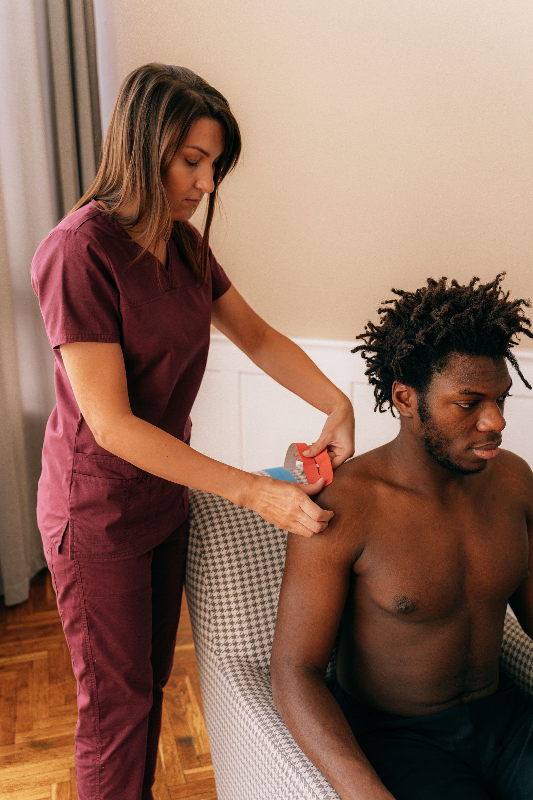 Physiotherapist applying kinesiology tape to a patient's shoulder in clinic