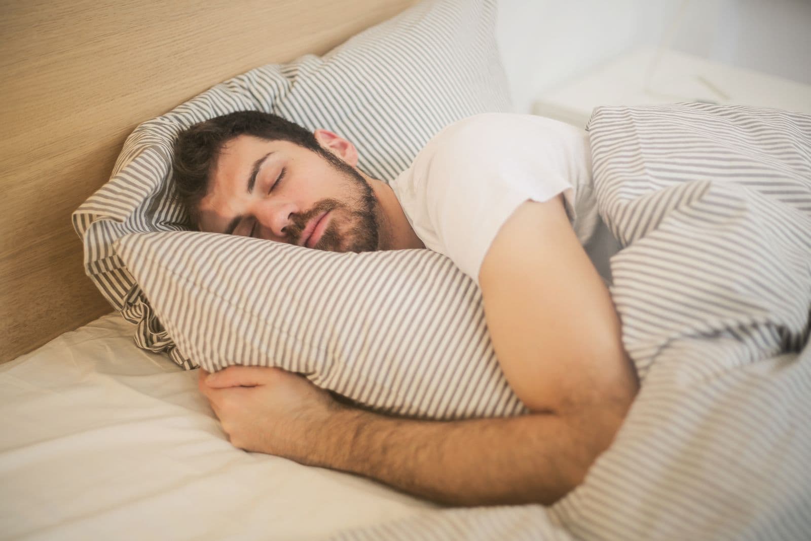 Man sleeping on a striped pillow, the ordinary GH-axis habit clinics try to sell as a peptide stack