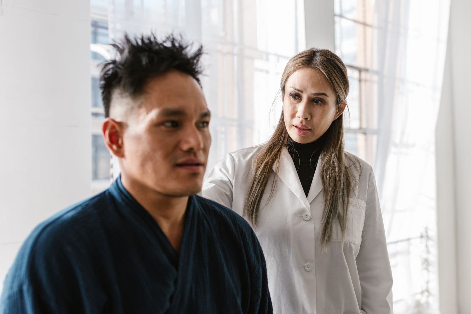 Clinician in a white coat standing with a patient during a clinic visit