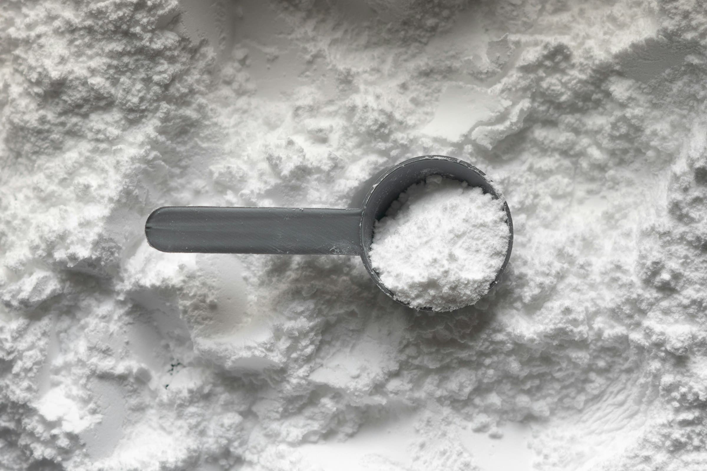 Gray scoop sitting in a field of white crystalline powder