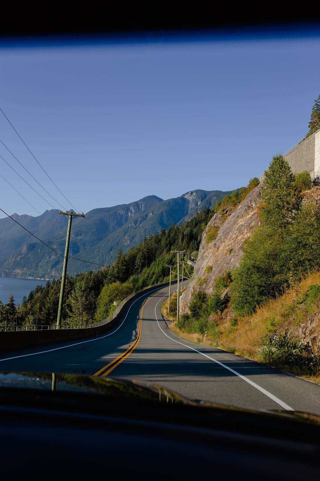 Coastal mountain road seen over a car hood, a drive day when the creatine tub stays home