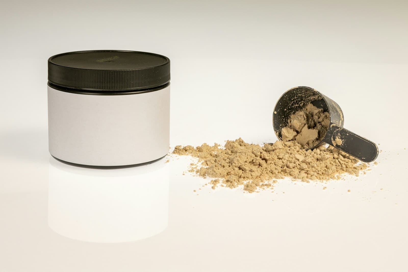 Unlabeled powder tub beside a spilled scoop, the jar that stays on the counter