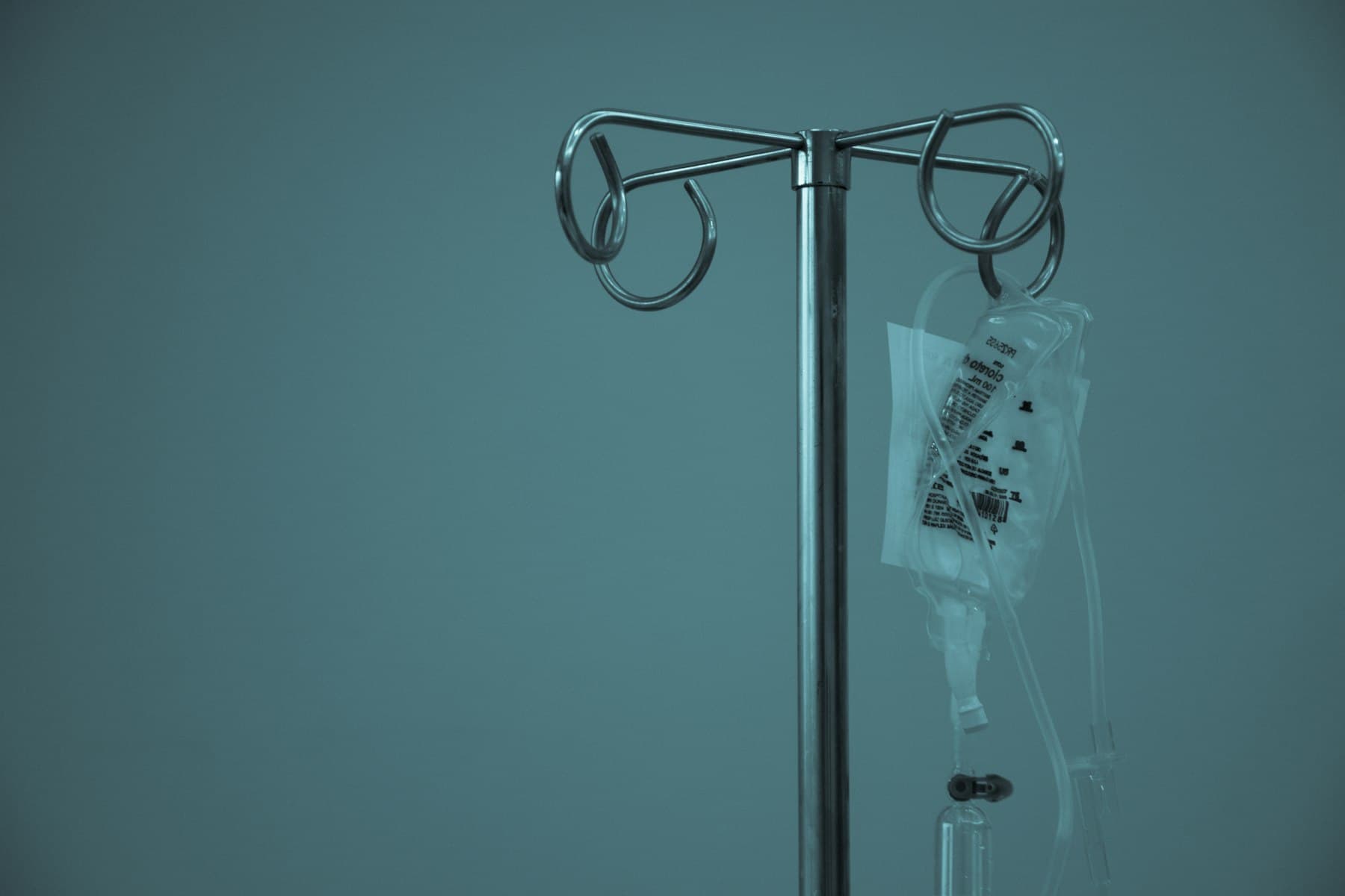 Hospital IV bag hanging on a stainless-steel drip stand, a clinical setting rather than a spa