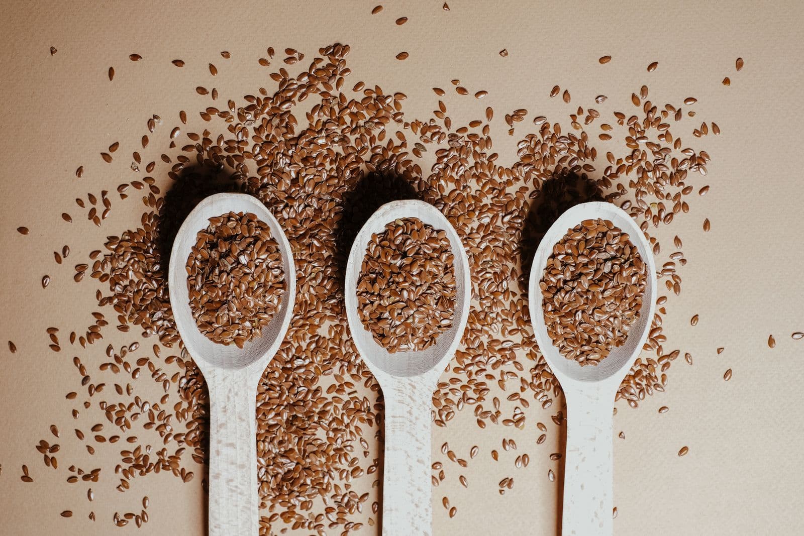 Flax seeds in three wooden spoons, a good food and a weak EPA/DHA converter