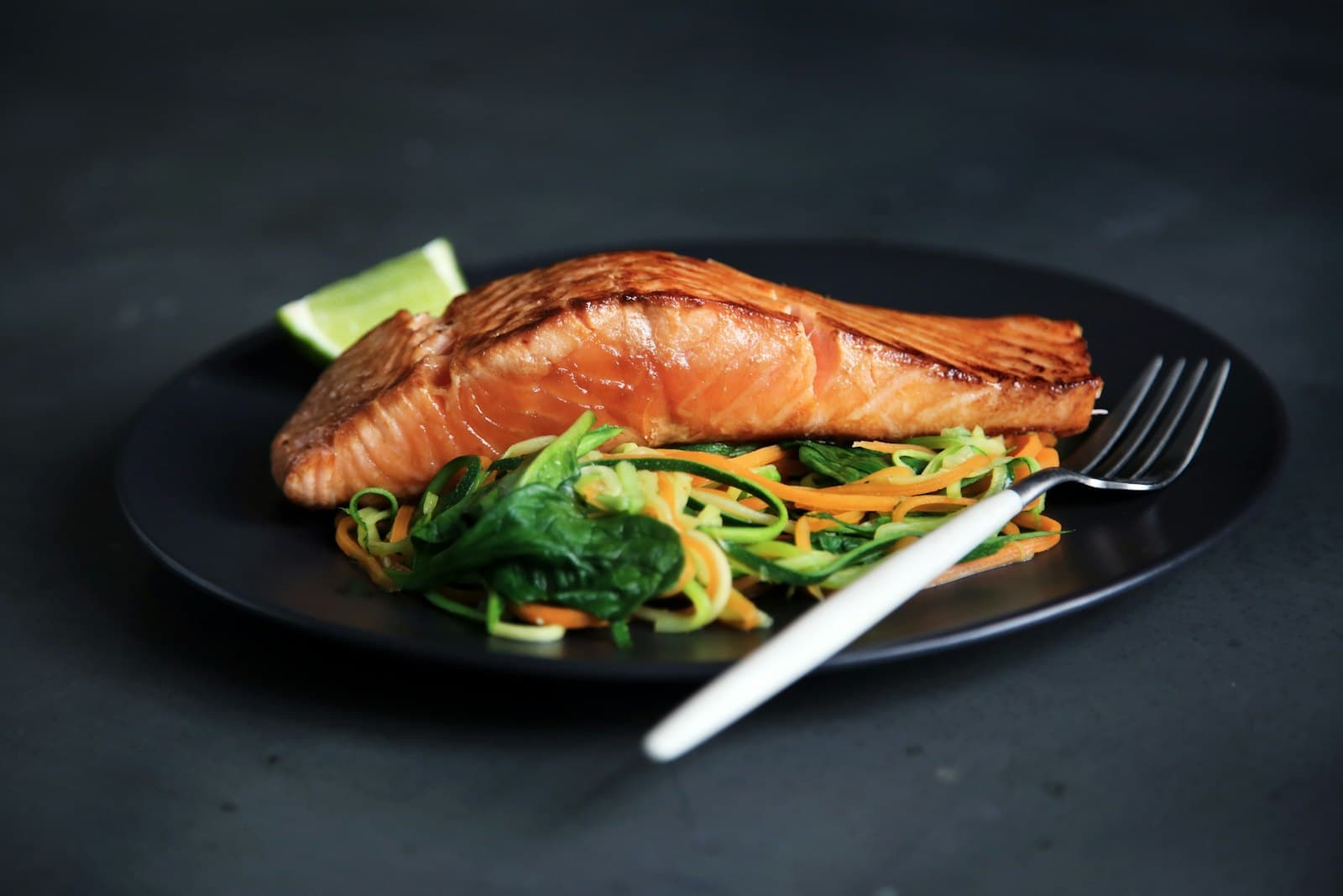 Cooked salmon fillet on a plate with vegetables, one of one to two seafood meals a week