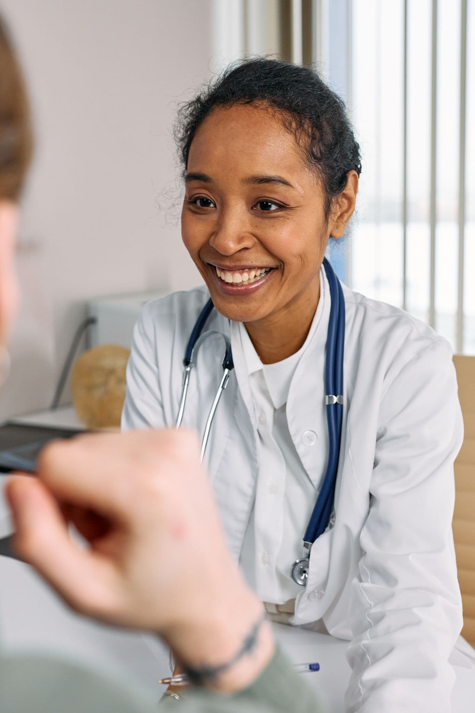 Physician in a white coat speaking with a patient during a clinic visit